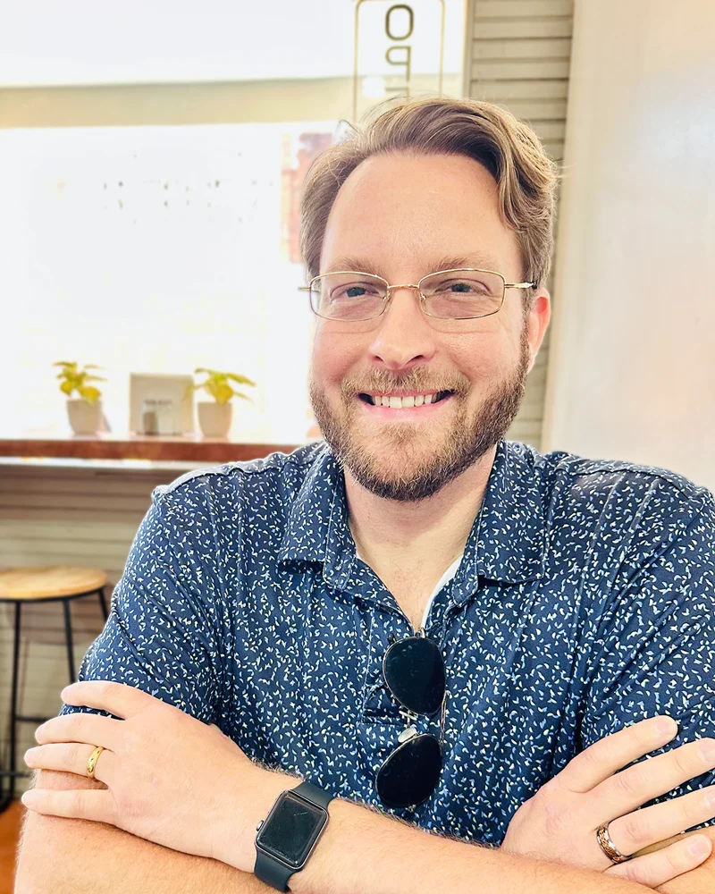 Dane Gustafson, founder of Viking Search Marketing, smiling with his arms crossed at a cafe table